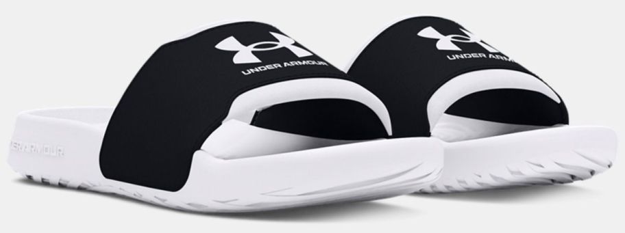 a pair of black and white boys under armour slides