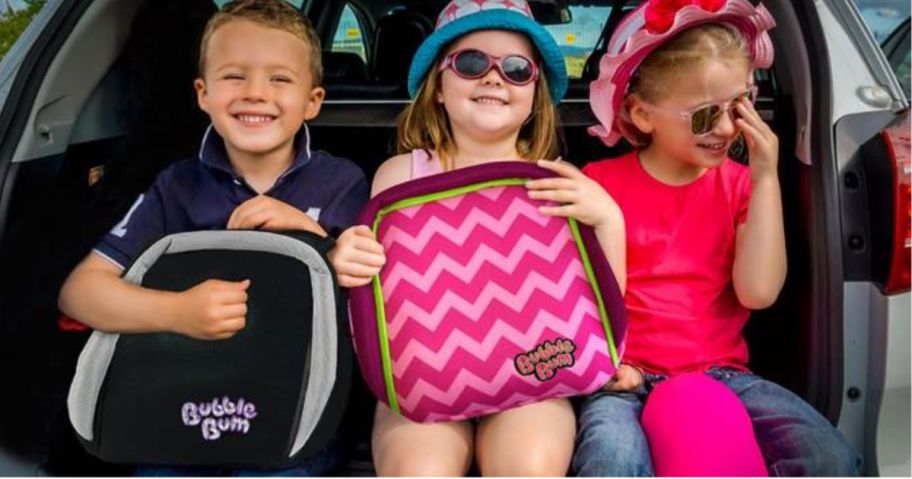 3 kids in the back of a car with 2 holding Bubblebum booster seats