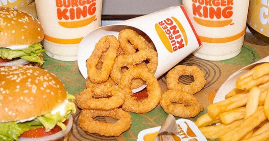 A carton of Burger King onion rings surrounded by other Burger King foods and drinks