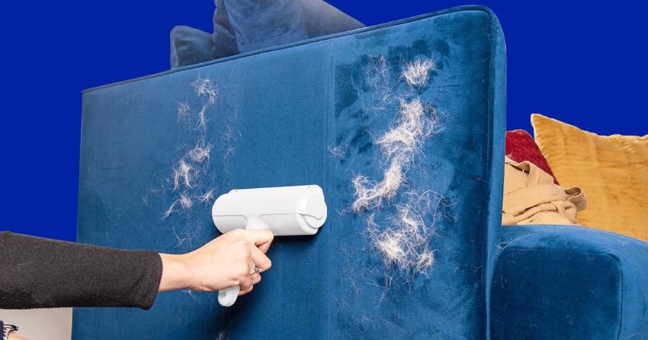 person using a pet hair remover on blue couch