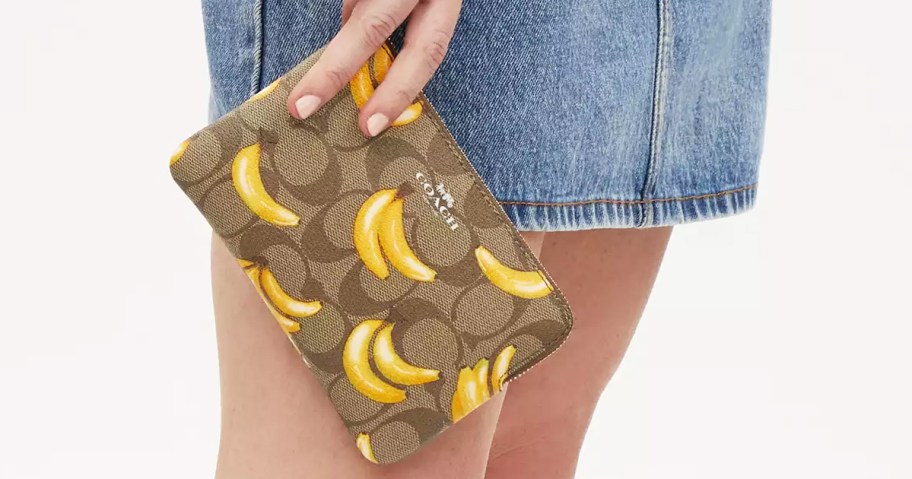 woman holding a banana print coach wristlet
