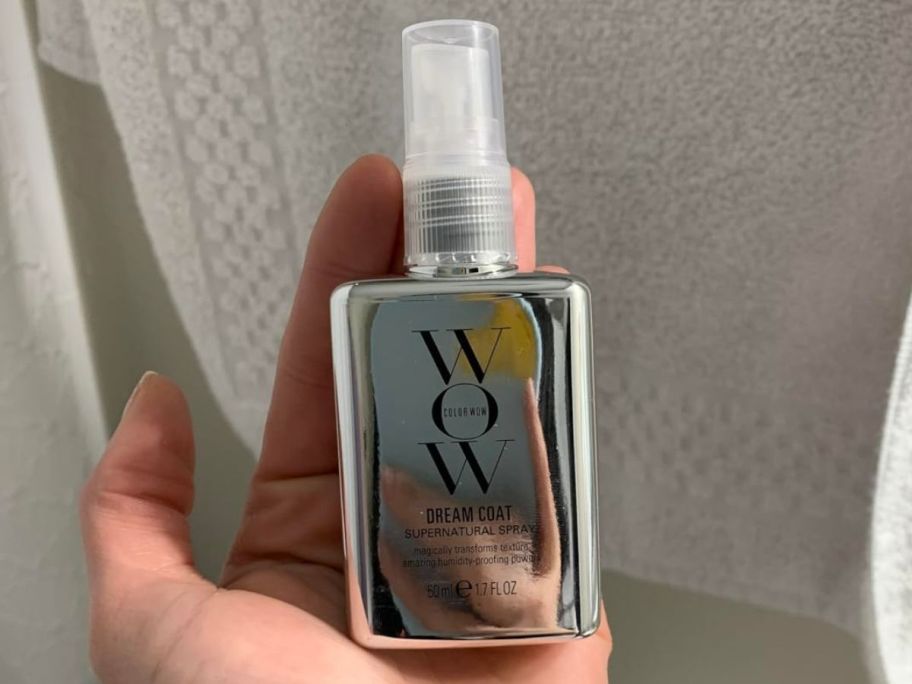 A bottle of Colorwow Dream Coat in the palm of a human hand