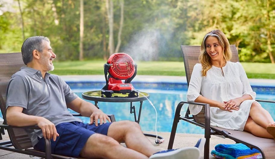 a red outdoor misting fan sitting on a table next to a swimming pool
