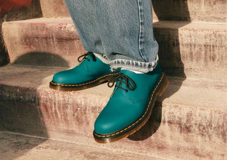 a model wearing a pair of teal green lace up oxfords