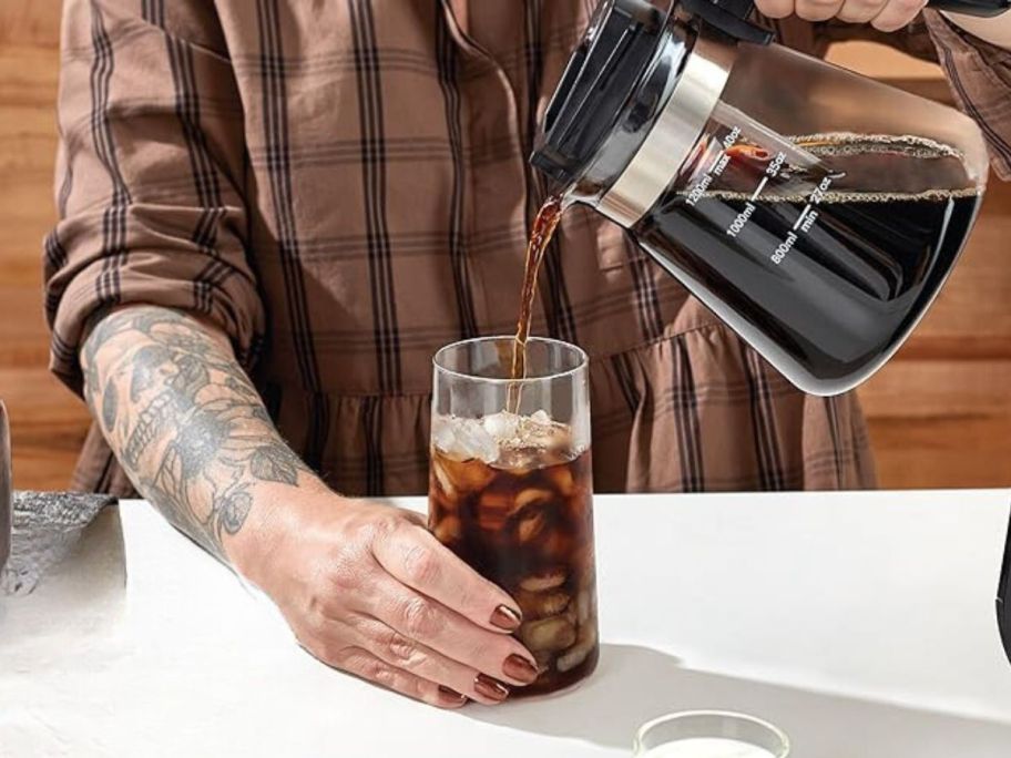 woman pouring coffee from Dash Rapid Cold Brew Coffee Maker 40-oz Glass Carafe into glass