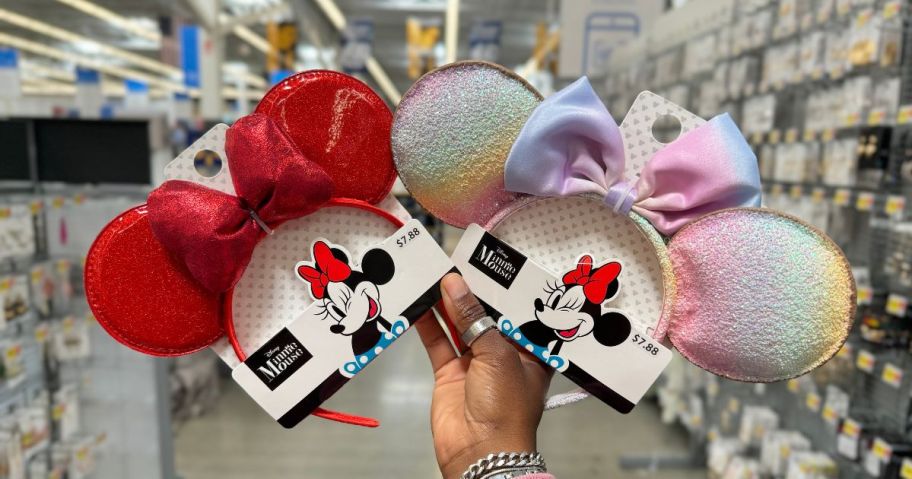 A person holding 2 pairs of Minnie Mouse Ears headbands