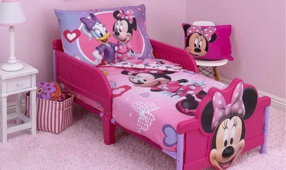 a toddlers bedroom with a minnie mouse bedding set on a minnie mouse bed.