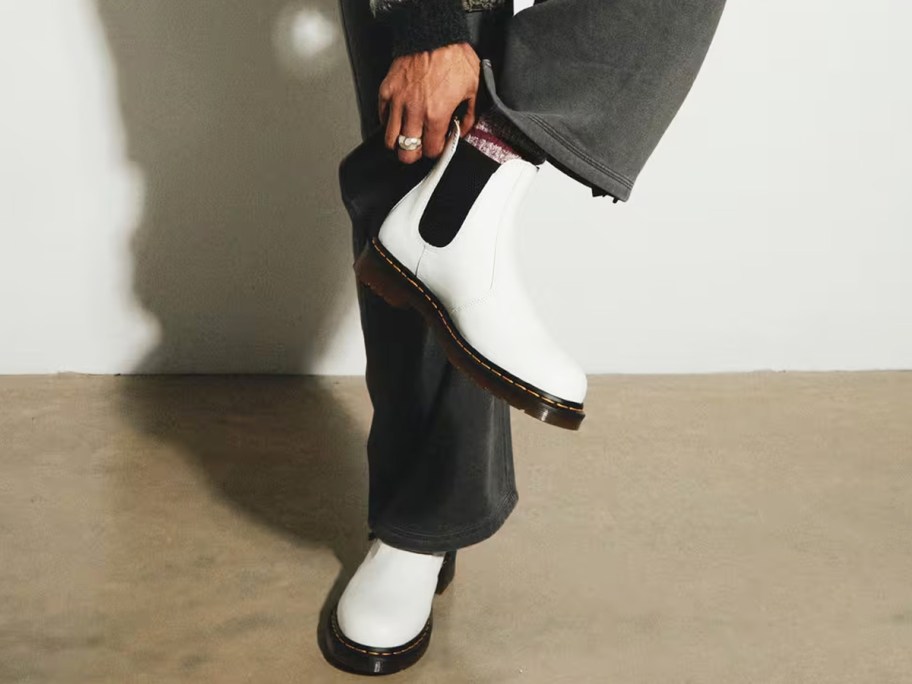 person pulling on a pair of white and black chelsea boots