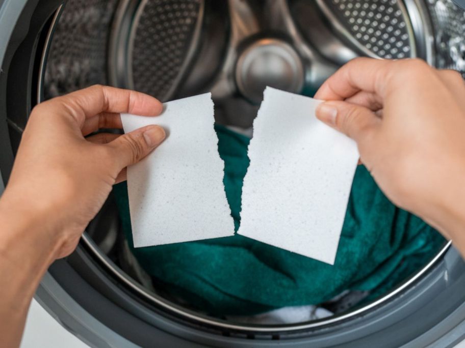 Woman's hands tearing an Earthwash Laundry detergent sheet before putting it in a washing machine