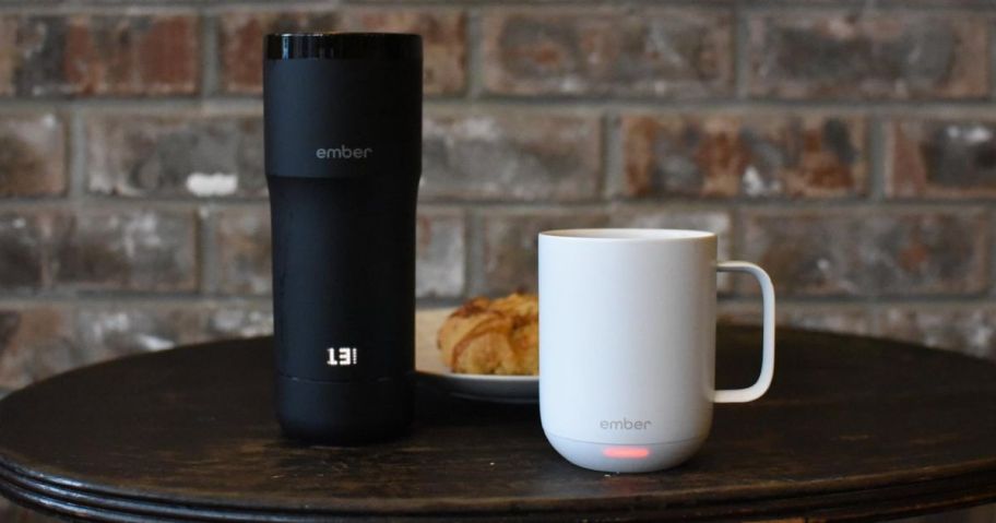 An Ember Tumbler and Mug next to a plate with a Croissant on it