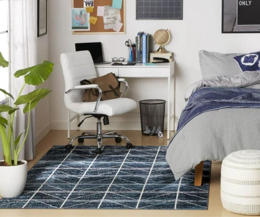 a navy blue geometric patterned rug on a hardwood floor in a bedroom