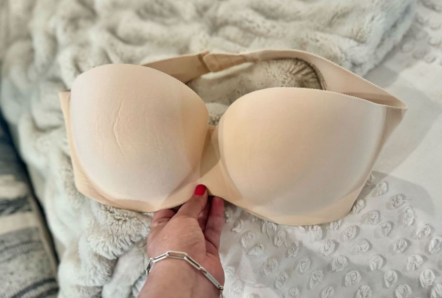 hand holding a strapless bra on bed