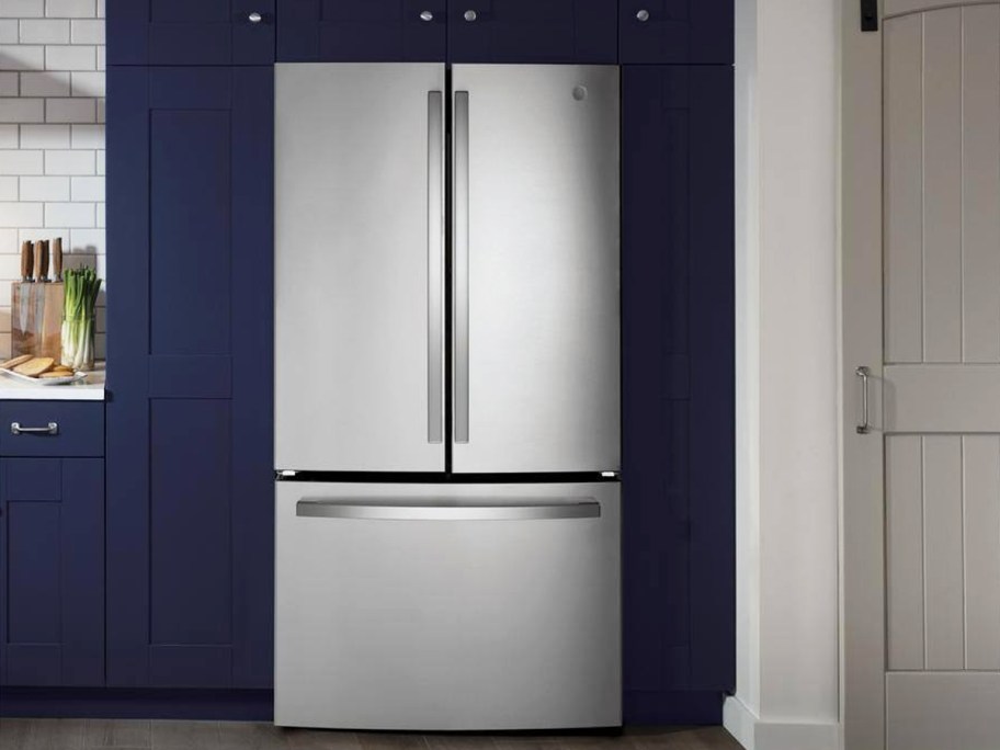 stainless steel fridge in kitchen with dark blue cabinets