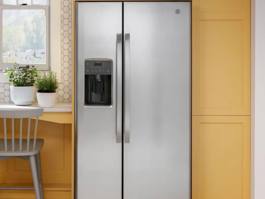 stainless steel refrigerator next to yellow cabinets in kitchen 
