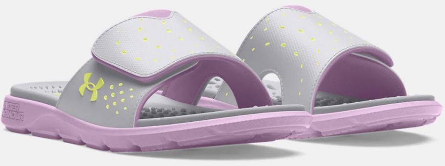 a pair of gray and pink girls under armour slides