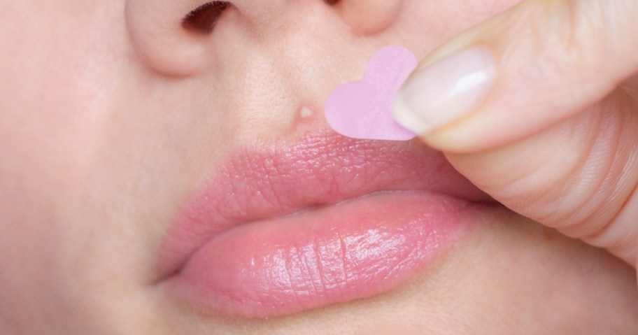 applying heart-shaped pimple patch to zip above lips