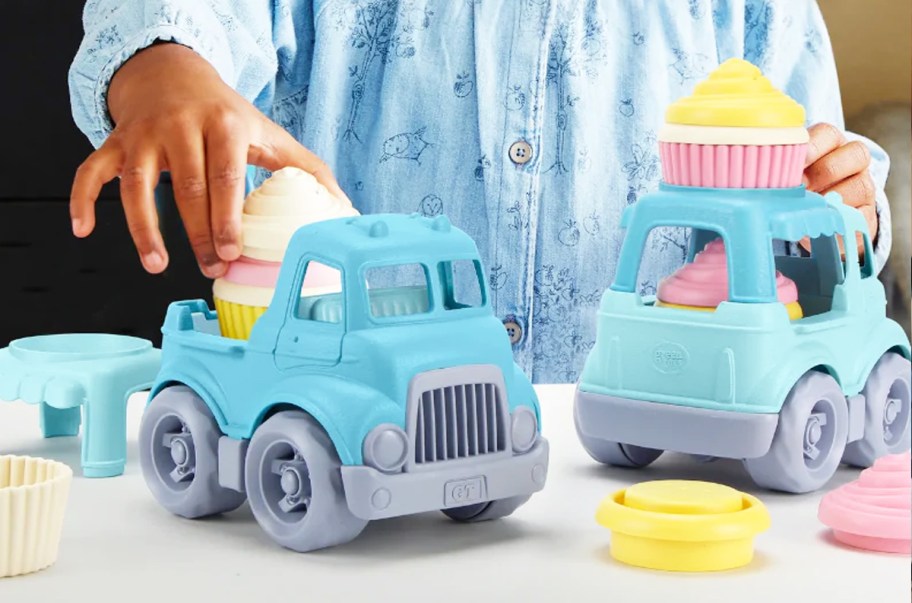 kid playing with blue trucks with cupcakes playset