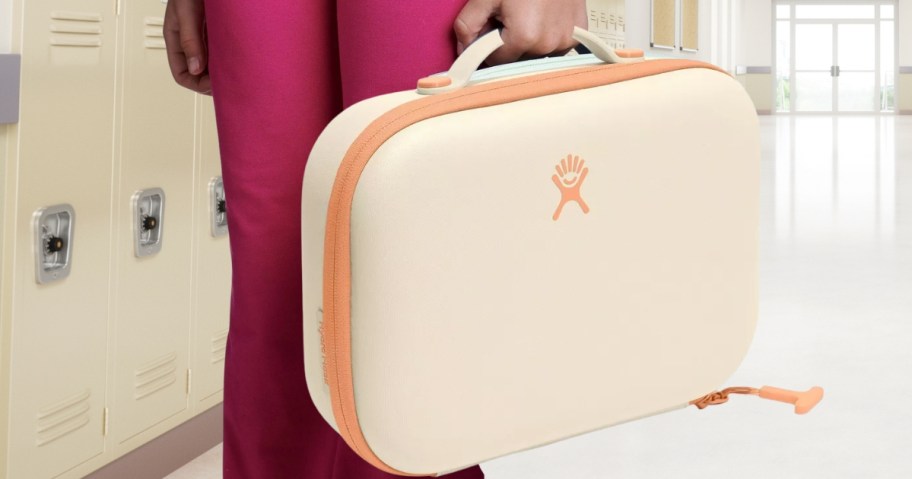 girl carrying a cream color lunch box