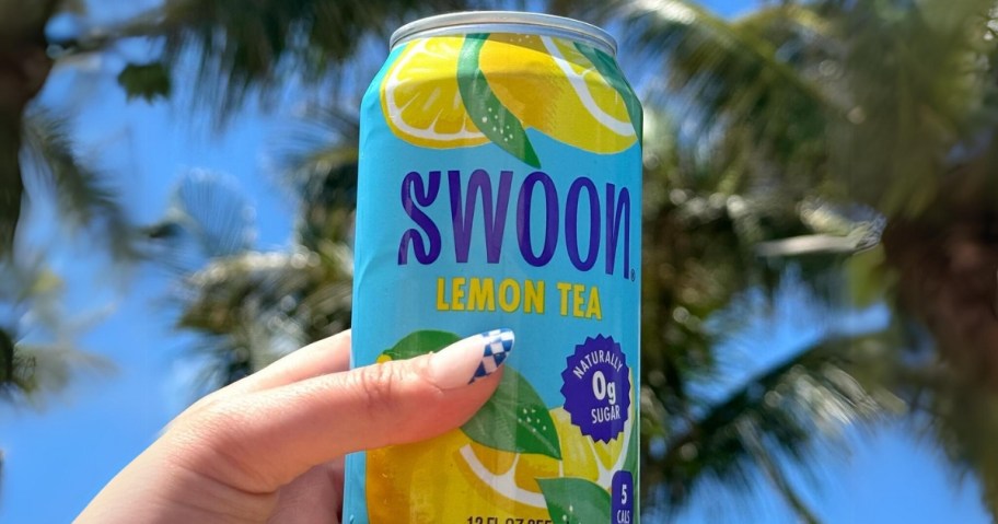 hand holding a SWOON Lemon Tea can, blue sky and palm trees in the background