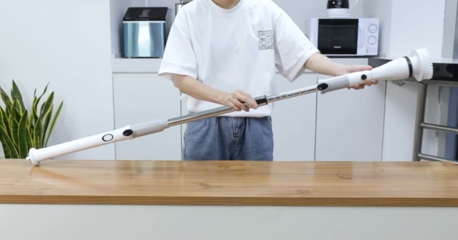 man holding an electric cordless scrubber brush tool showing the extendable handle