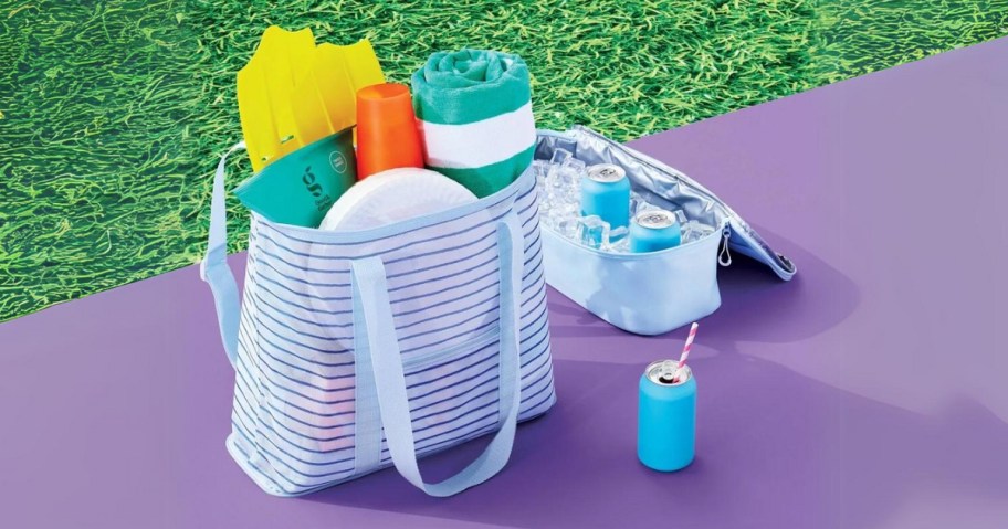 striped mesh tote bag with beach towels and lotion in it next to a cooler bag with soda and ice