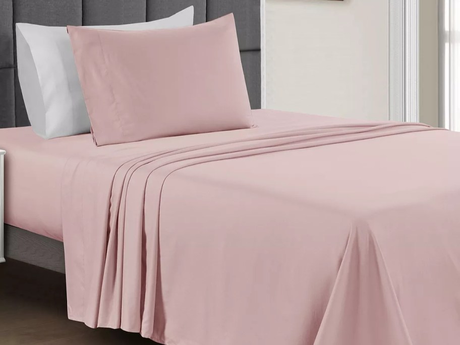bed with pink sheet set on it