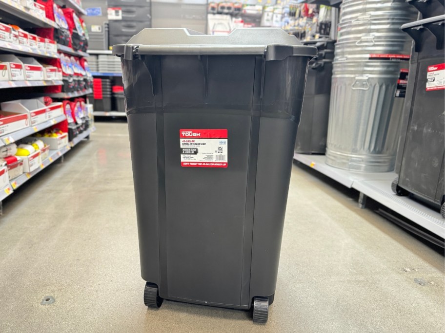 large black garbage can with wheels and lid in the middle of an aisle at Walmart
