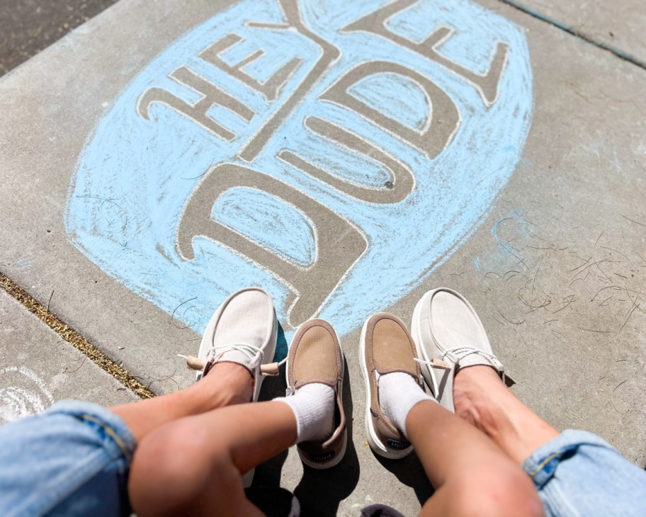 kids and womens feet on heydude chalk sign