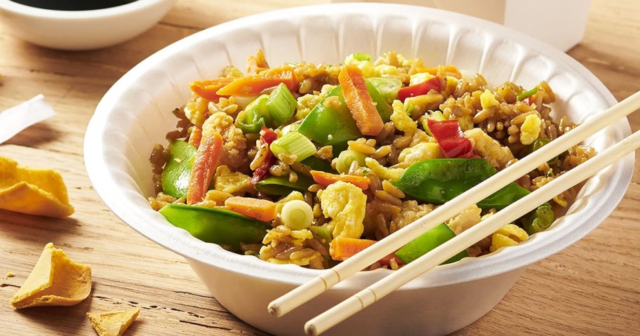 fried rice and veggies in foam bowl with chopsticks on top