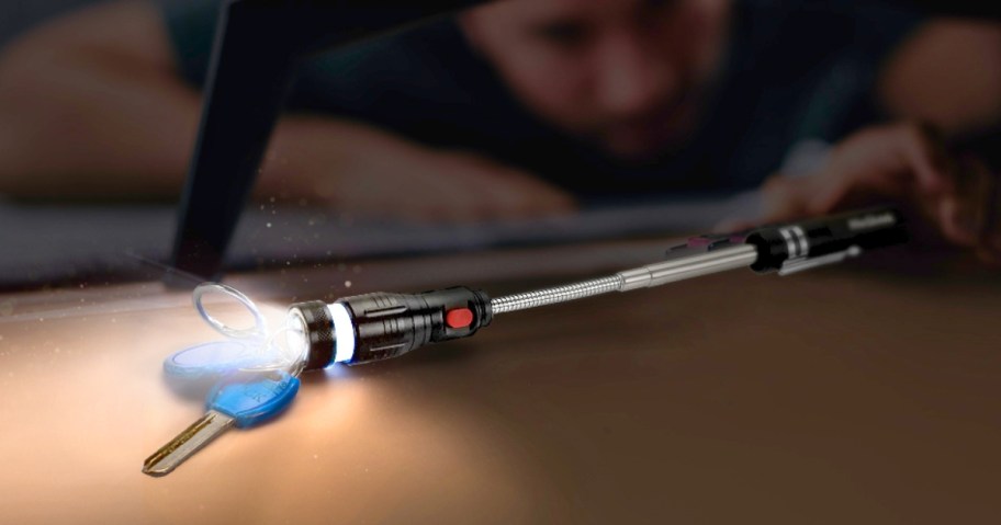 man using a telescoping LED magnetic pickup tool to get a set of keys