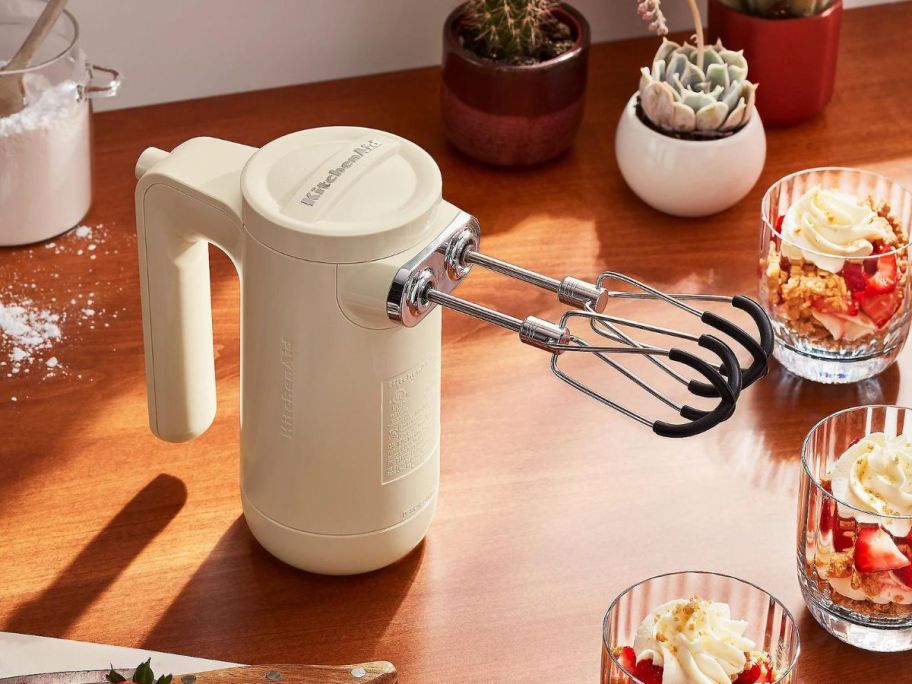 KitchenAid Cordless 7-Speed Hand Mixer w/ Flex Edge Beaters on counter with desserts around it