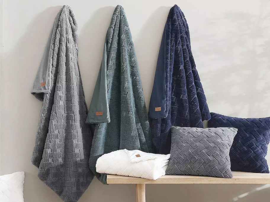 grey, green, and blue throw blankets hanging on wall hooks