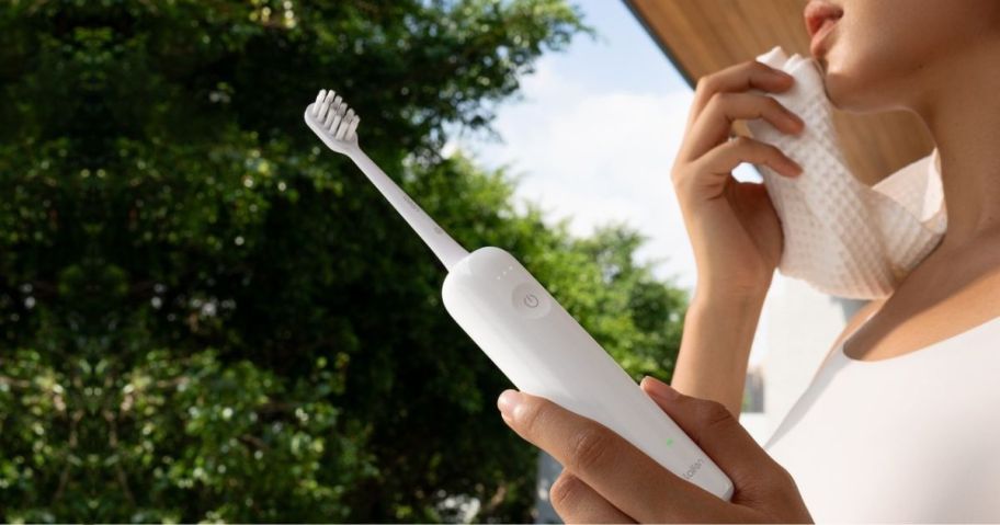 woman standing outside on porch holding a Lafein Wave Electric Toothbrush in her hand