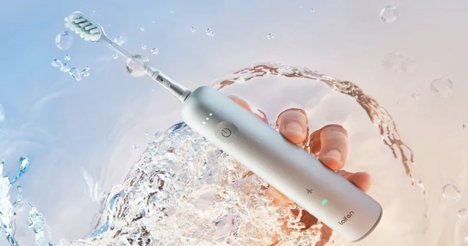 hand holding electric toothbrush in water