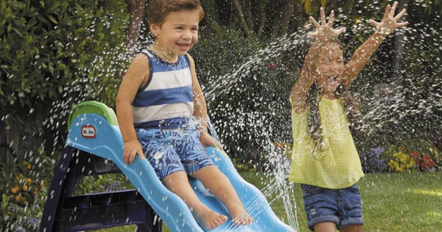 Little Boy on a Little Tikes Slide with water spraying off of it