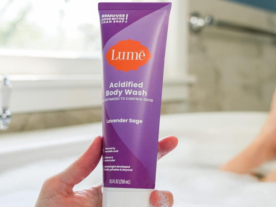 hand holding a purple tube of Lume Acidified Body Wash
