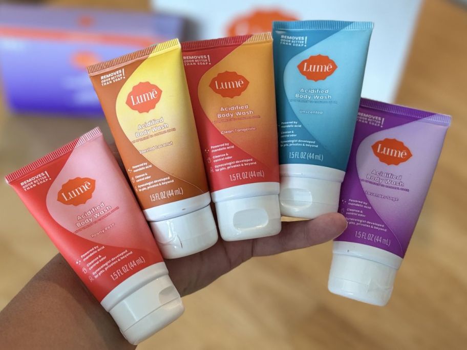 Hand holding 5 tubes of Lume Mini body washes