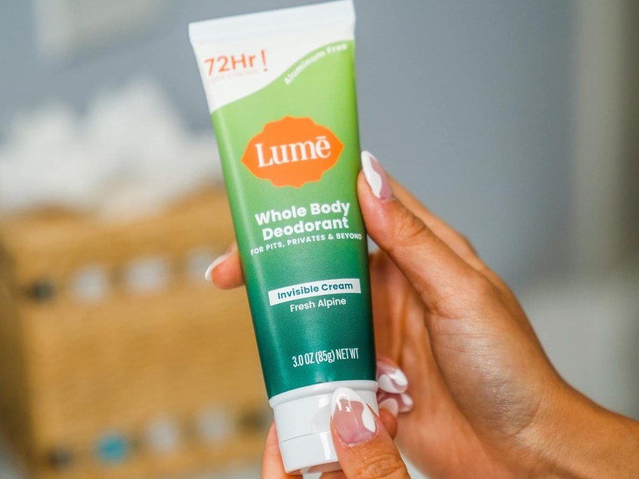 hands holding a green and white tube of Lume Whole Body Deodorant Cream