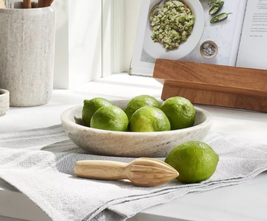 a decorative marble bowl filled with green apples and sitting on a kitchen counter