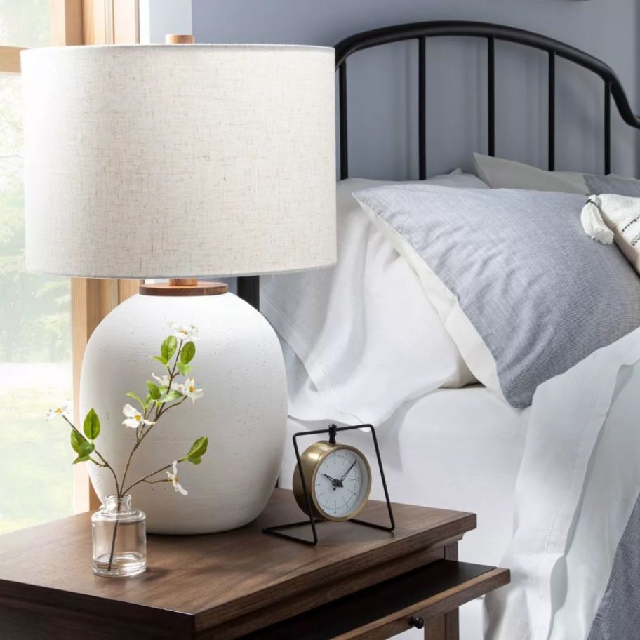 a white table lamp on a bad side table next to a bed