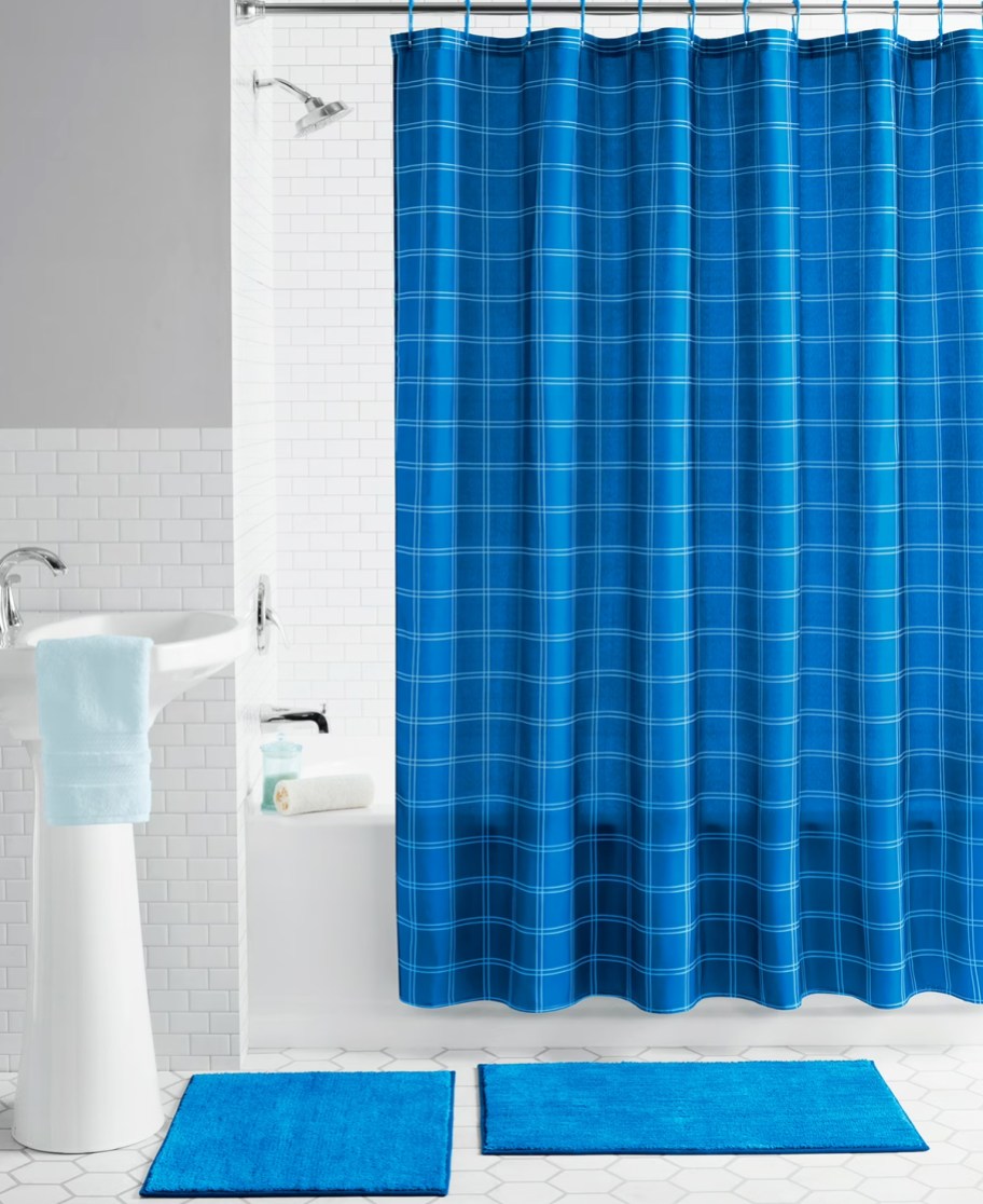blue plaid print shower curtain with 2 blue rugs on floor