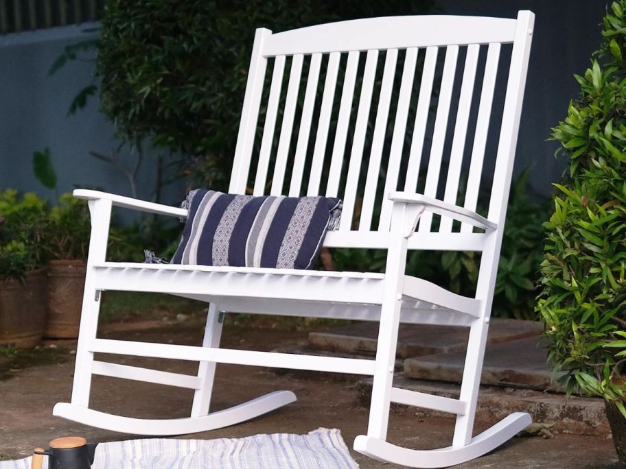 A Mainstays Double Rocking Chair outside with a throw pillow on it