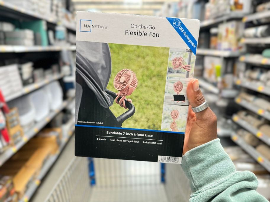 A hand holding a portable fan in a store