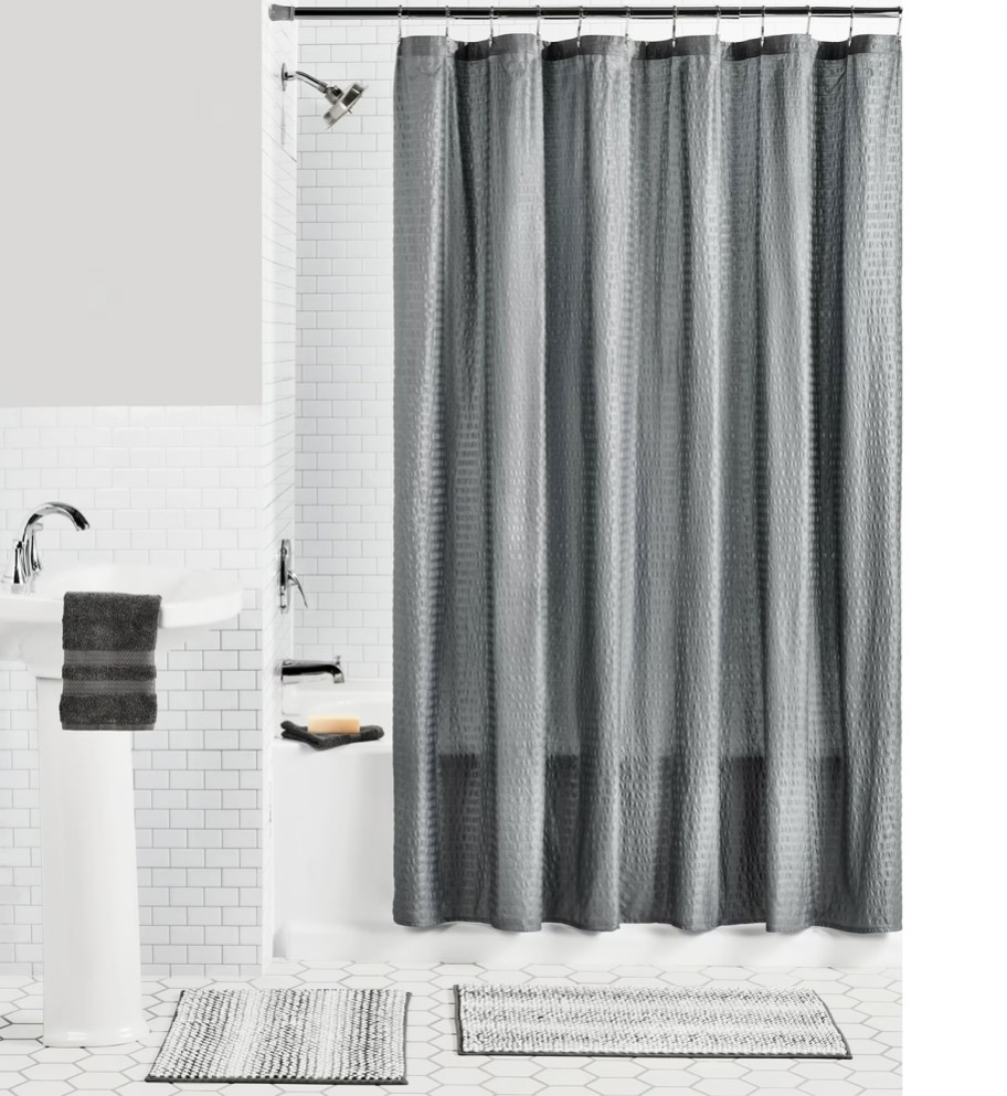 grey textured shower curtain in bathroom with 2 coordinating rugs on floor