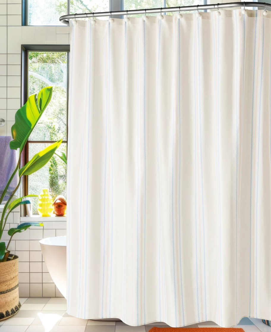 white shower curtain hanging in front of tub