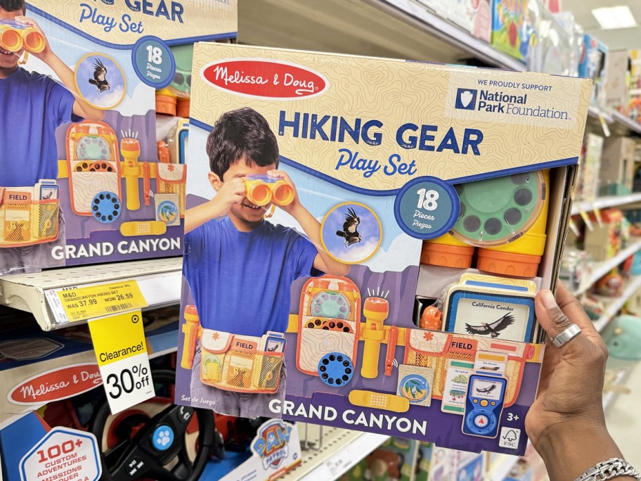 hand grabbing Melissa & Doug Hiking Gear Play Set from store shelf