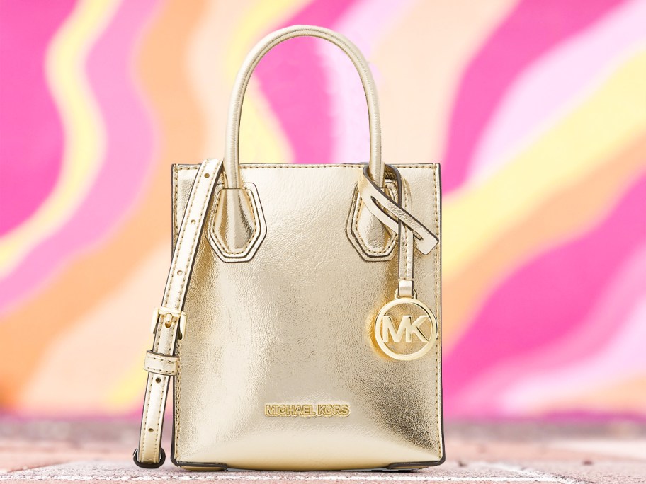 metallic gold michael kors bag with pink, orange, and yellow wall in background