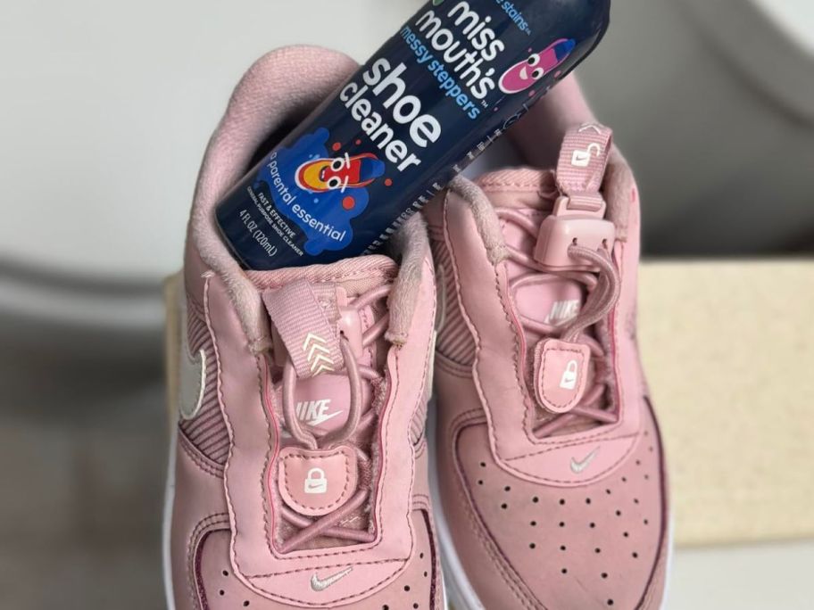 A pair of Nike shoes with a bottle of Miss Moth's messy Stepper Shoe Cleaner