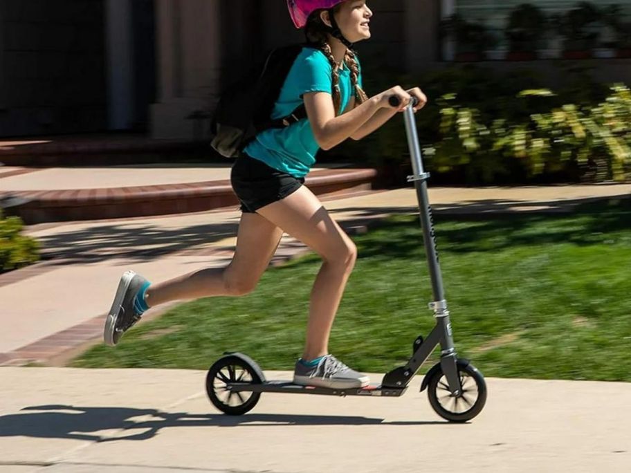 A child riding a Mongoose Trace Folding Scooter