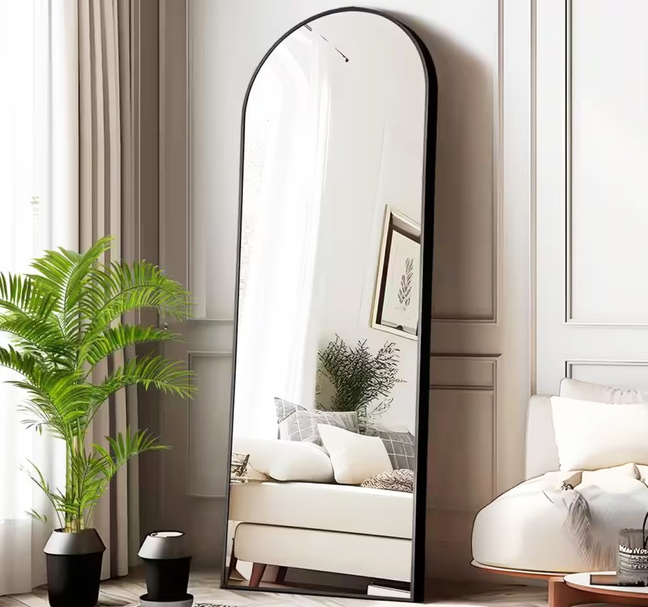 black arched wall mirror leaning against wall